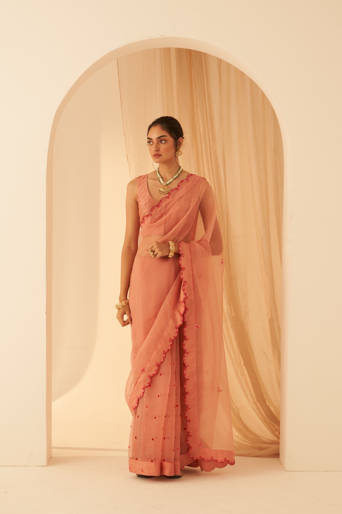 Peach organza aari hand embroidered saree with beautiful butis allover & scallop border paired with an organic cotton stitched petticoat