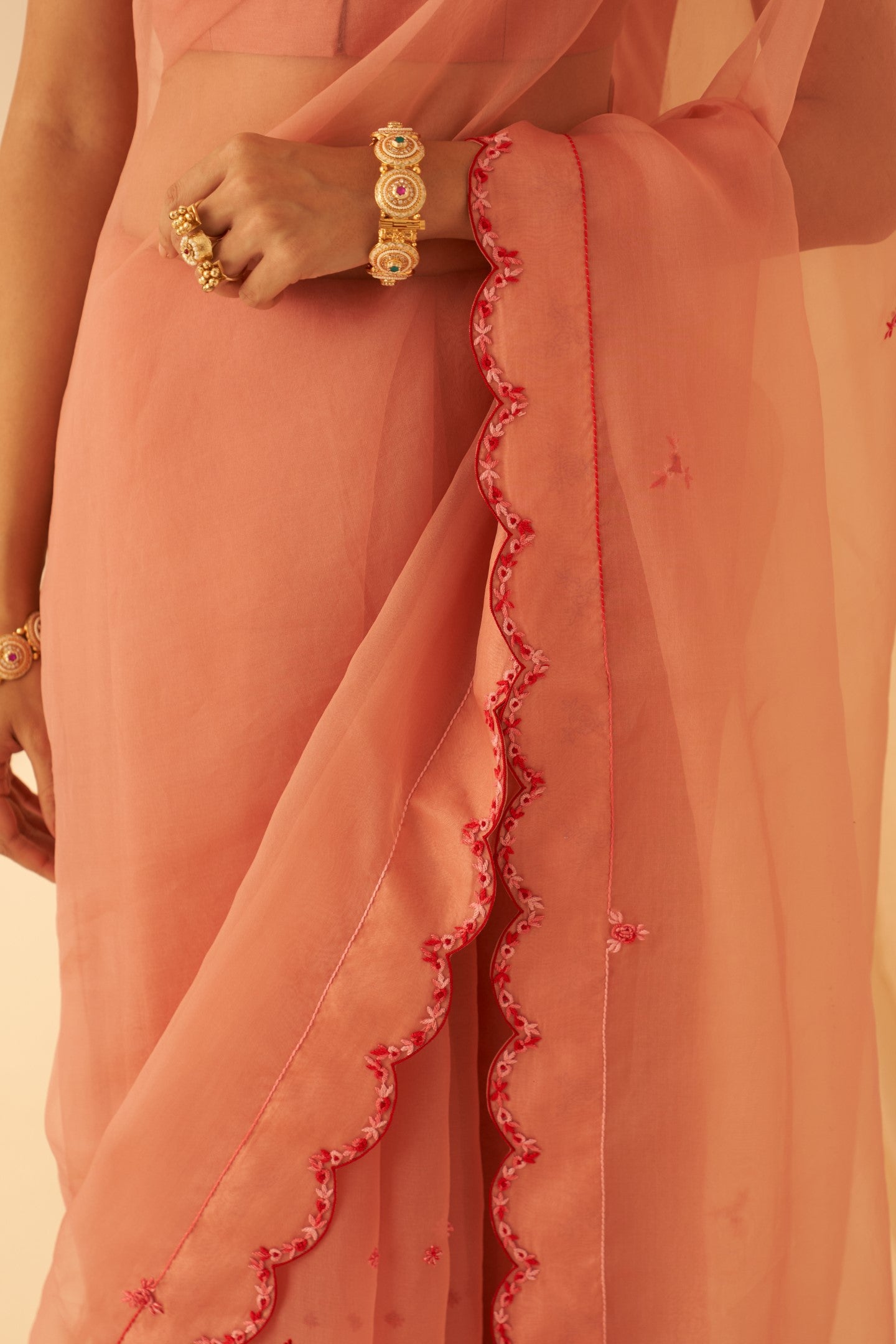 Peach organza aari hand embroidered saree with beautiful butis allover & scallop border paired with an organic cotton stitched petticoat